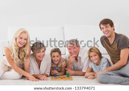 Family looking at the camera with board games in sitting room