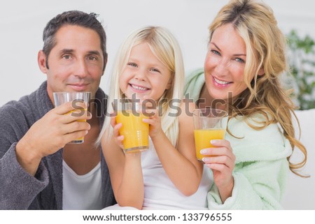 Family drinking glasses of orange juice in the living room