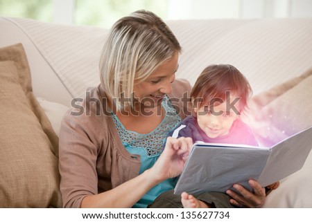 Mother reading storybook beaming purple light with son sitting on the couch