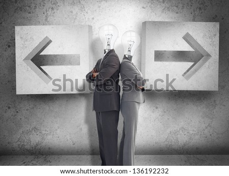 Business partners with heads for light bulbs standing back to back in front of two arrows on a grey wall