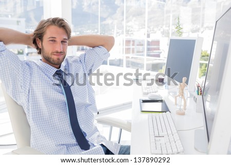 Smiling designer using his tablet pc while team works behind