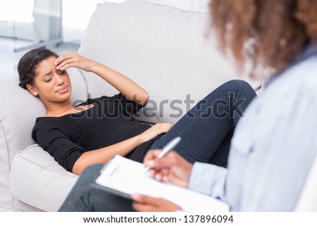 Woman crying at therapy while therapist takes notes