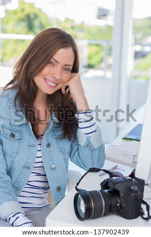 Smiling photographer at desk on computer in modern office
