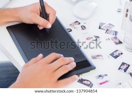 Male hands using graphics tablet on desk with photography