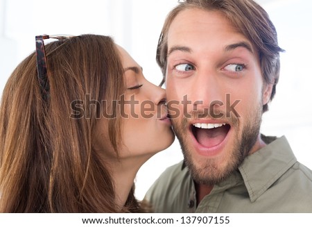 Pretty woman kissing man with beard on the cheek