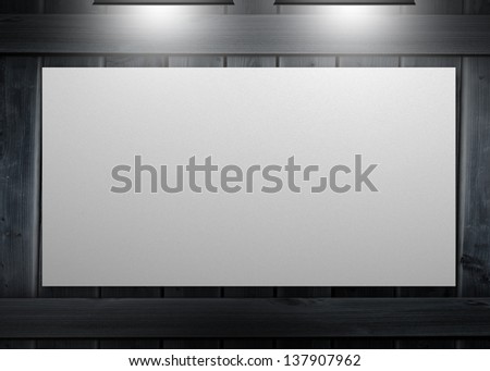 White copy space poster hung on a wall and lighted with spotlights