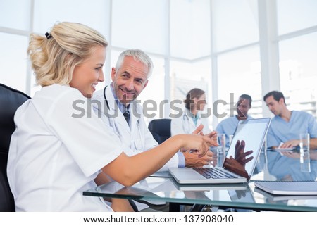 Two smiling doctors looking at a laptop in office