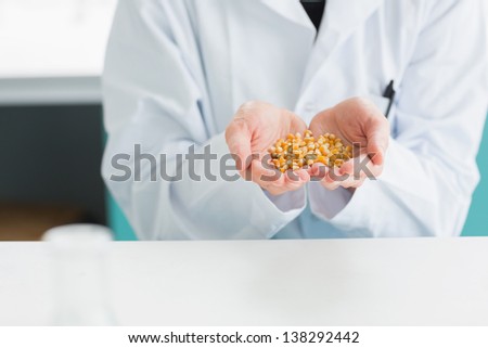 Student in lab coat holding grain in the laboratory