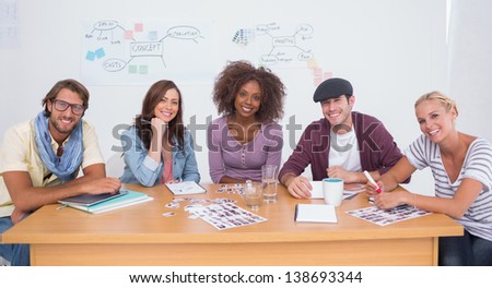 Creative team smiling at camera sitting at large desk in office