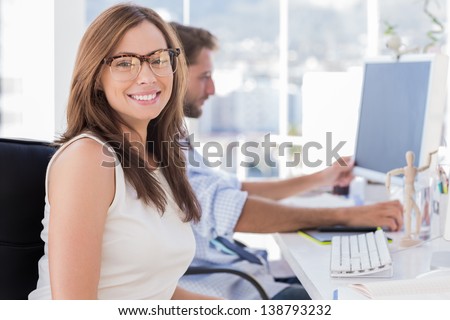 Portrait of smiling designer with colleague working behind her