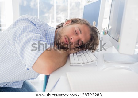 Man sleeping on his desk in bright modern office