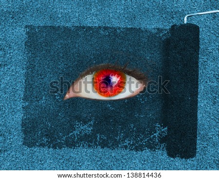 Paint roller revealing a red eye on blue texture