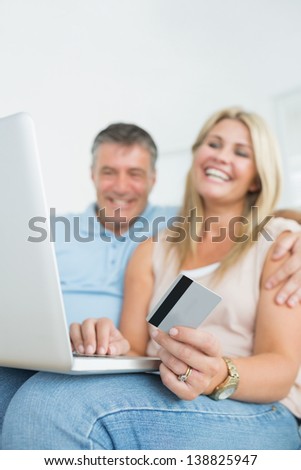 Couple sitting on sofa and using laptop to shop online