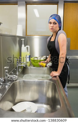 Unhappy woman washing the dishes in the restaurant