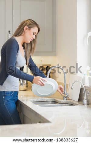 Woman doing the washing up in kitchen