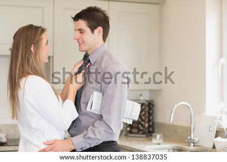 Wife fixing husbands tie in kitchen