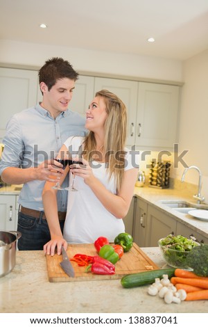 Couple cooking and clinking wine glasses in kitchen
