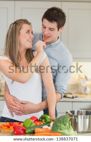 Woman having fun by feeding man in kitchen