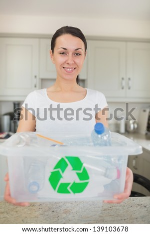 Woman holding full recycling bin in kitchen