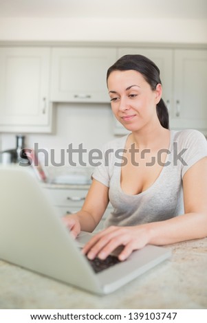Woman typing on a laptop in kitchen