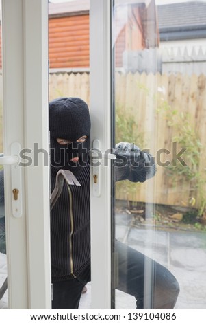 Burglar opening the terrace door with cro bar