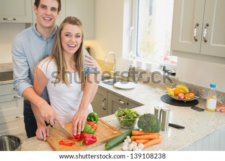 Young couple smiling and working in the kitchen
