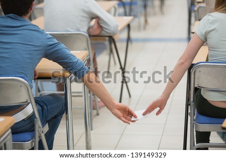 Students sitting in a classroom and cheating while doing a test