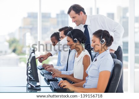Manager explaining something to his employee in a call centre