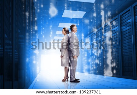 Business people standing back to back in data center with glowing matirx raining down