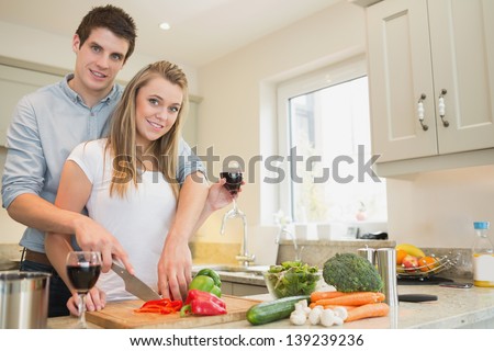 Couple cooking and drinking wine together in kitchen