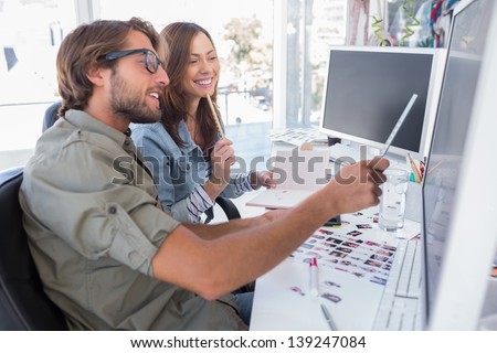 Photo editors working together at desk and smiling in bright modern office
