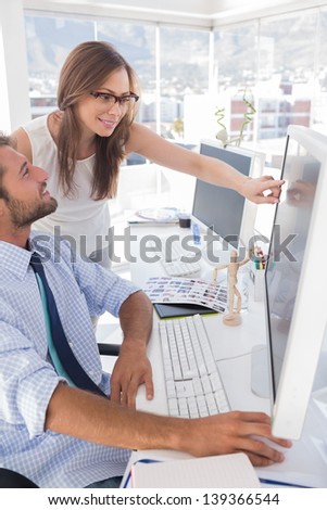 Photo editors looking at computer screen in office at desk