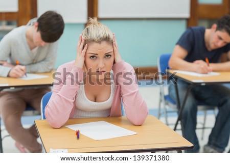 Thinking student sitting at a table in a classroom while having an examination