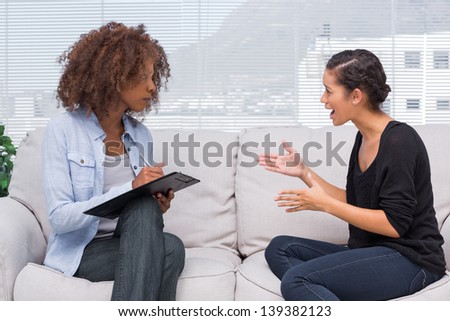 Upset woman speaking to her therapist while she is taking notes