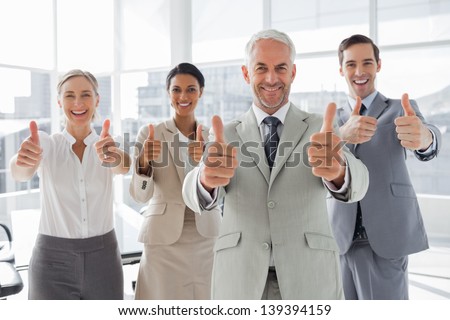 Business people giving thumbs up in the meeting room