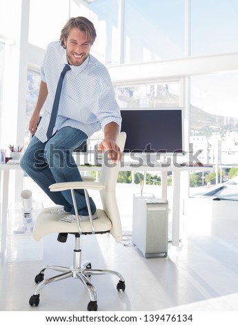 Man surfing his office chair and smiling in modern office