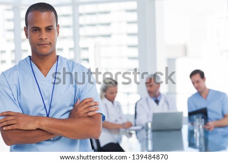 Serious doctor with arms crossed standing in front of his team