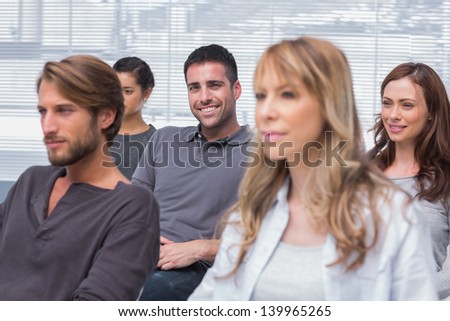 Patients listening in group therapy with one man smiling at the camera in office