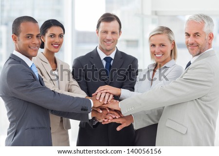 Group of smiling business people piling up their hands together in the workplace