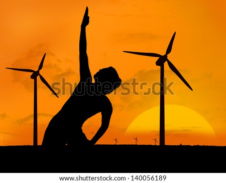 Woman practicing yoga under sunset in front of wind turbines