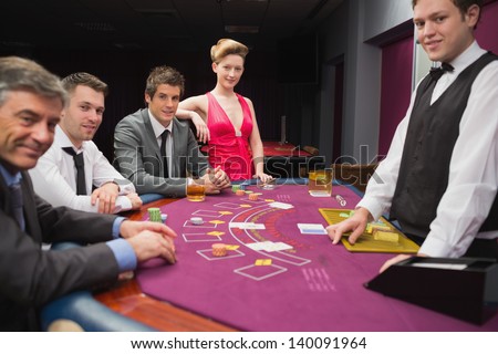 People sitting at blackjack table and smiling in the casino