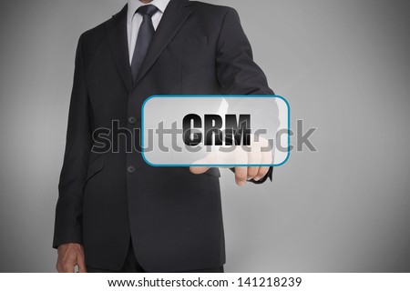 Businessman selecting tag with crm written on it on grey background