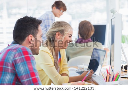 Designers laughing and working together on computers