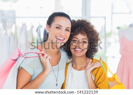 Smiling friends holding shopping bags and smiling at camera