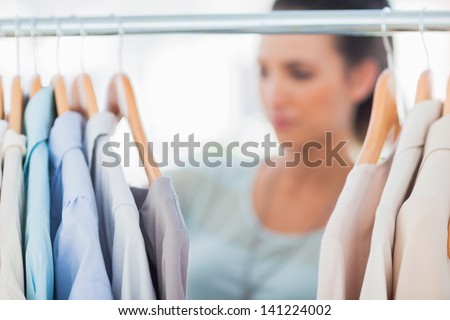 Fashion woman choosing clothes on clothes rail in a studio