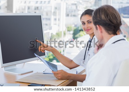Doctor showing the screen of a computer to a colleague while they are working together