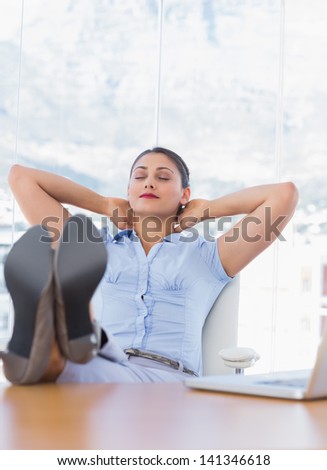 Pretty businesswoman relaxing in her office with her foot on the desk