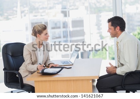 Smiling businesswoman interviewing businessman in the office