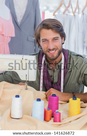 Fashion designer using sewing machine and smiling to the camera