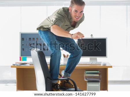 Smiling man surfing his office chair and having fun